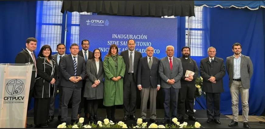 Group of professionals on stage posing for a ceremony, with a blue banner in the background reading 'INAUGURACIÓN' and a clear podium on the left.