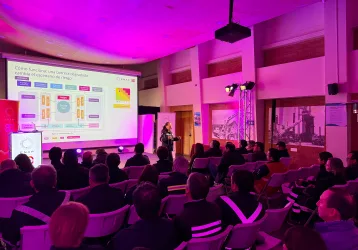 Iluminación Led para eventos corporativos - FBAudio – Pantallas Led – Streaming – Amplificación Speaker presenting a slide on a large screen to a seated audience in a conference hall with purple lighting, ENAP banner visible.